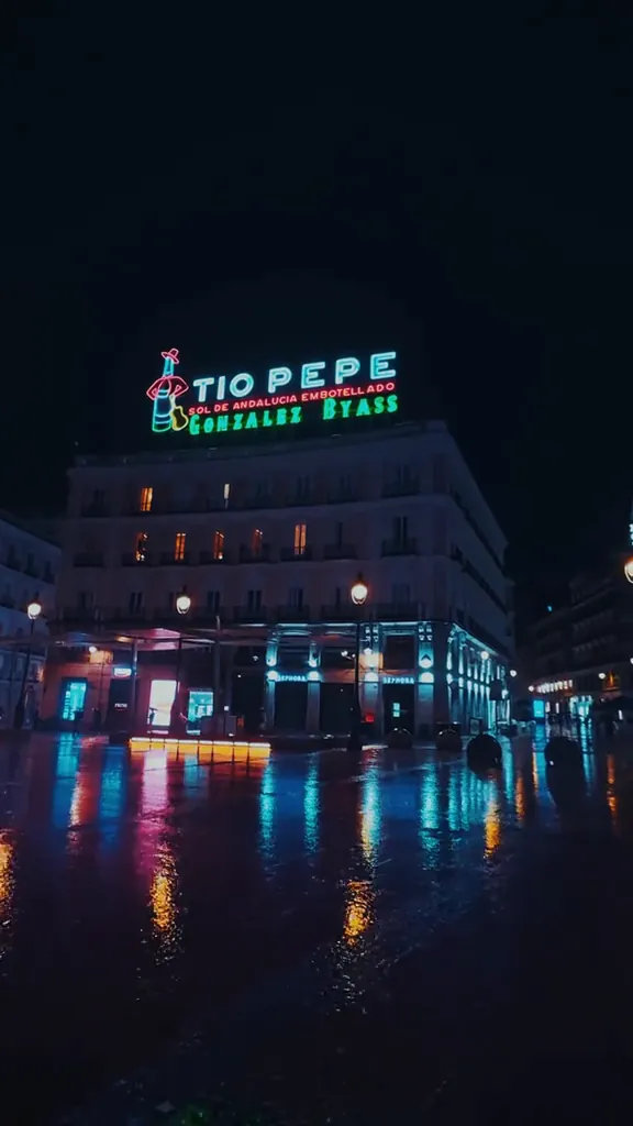 Puerta del Sol de noche, con el suelo mojado y el cartel de Tío Pepe